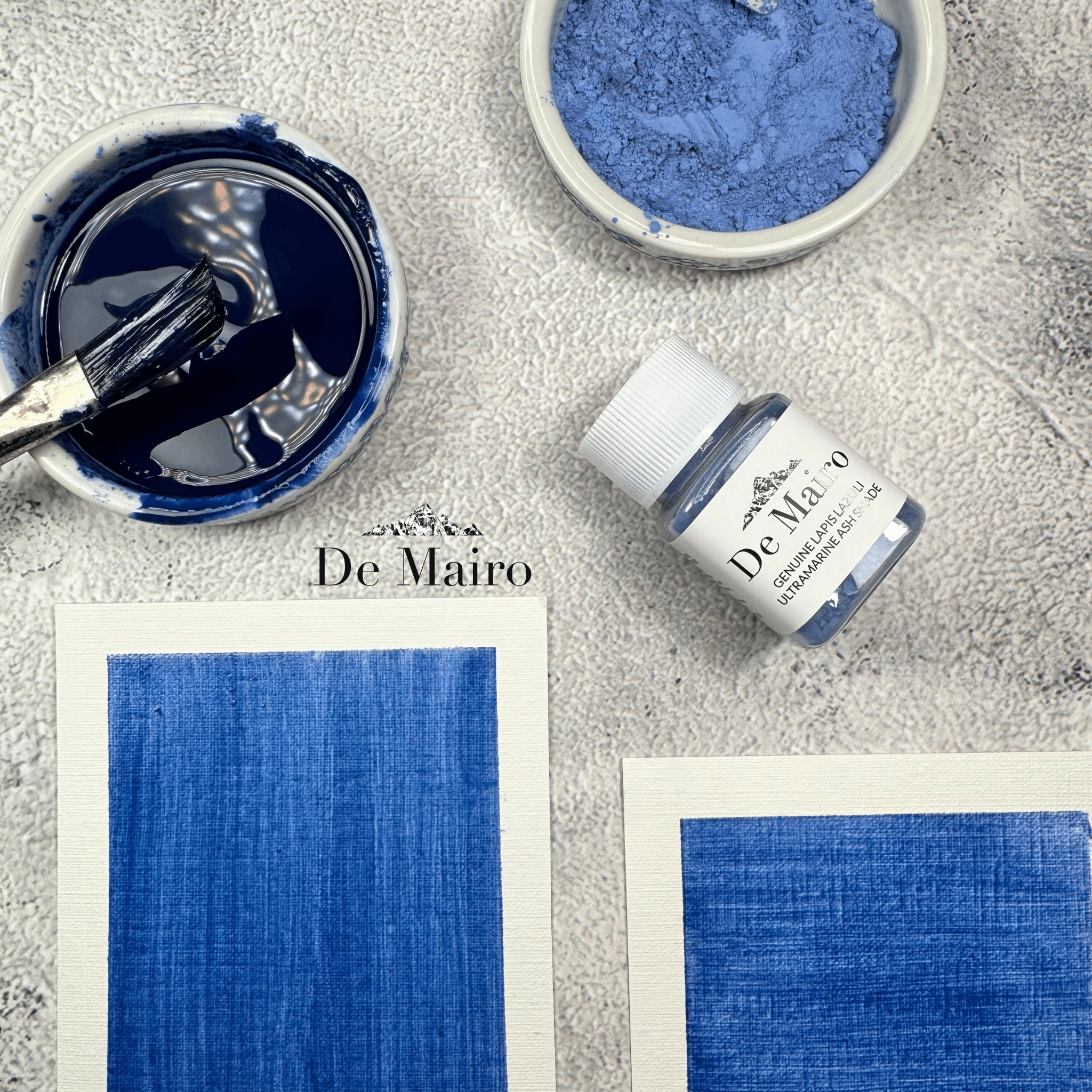 Ultramarine Ash Shade oil medium swatches near a dish with powdered pigment, a pigment jar, and another dish with blended pigment with paintbrush in it