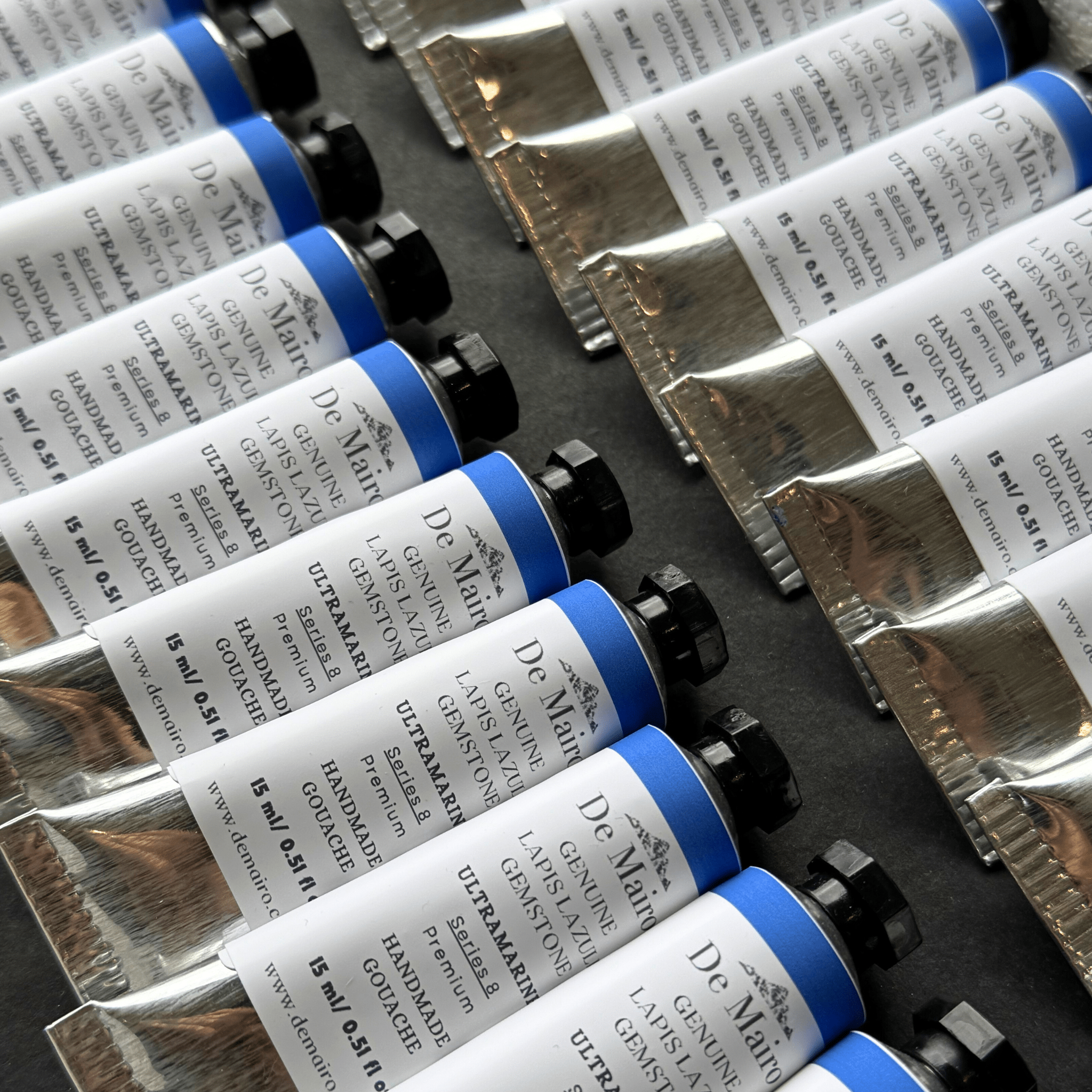 Row of DeMairo gouache tubes with visible labels on a dark surface
