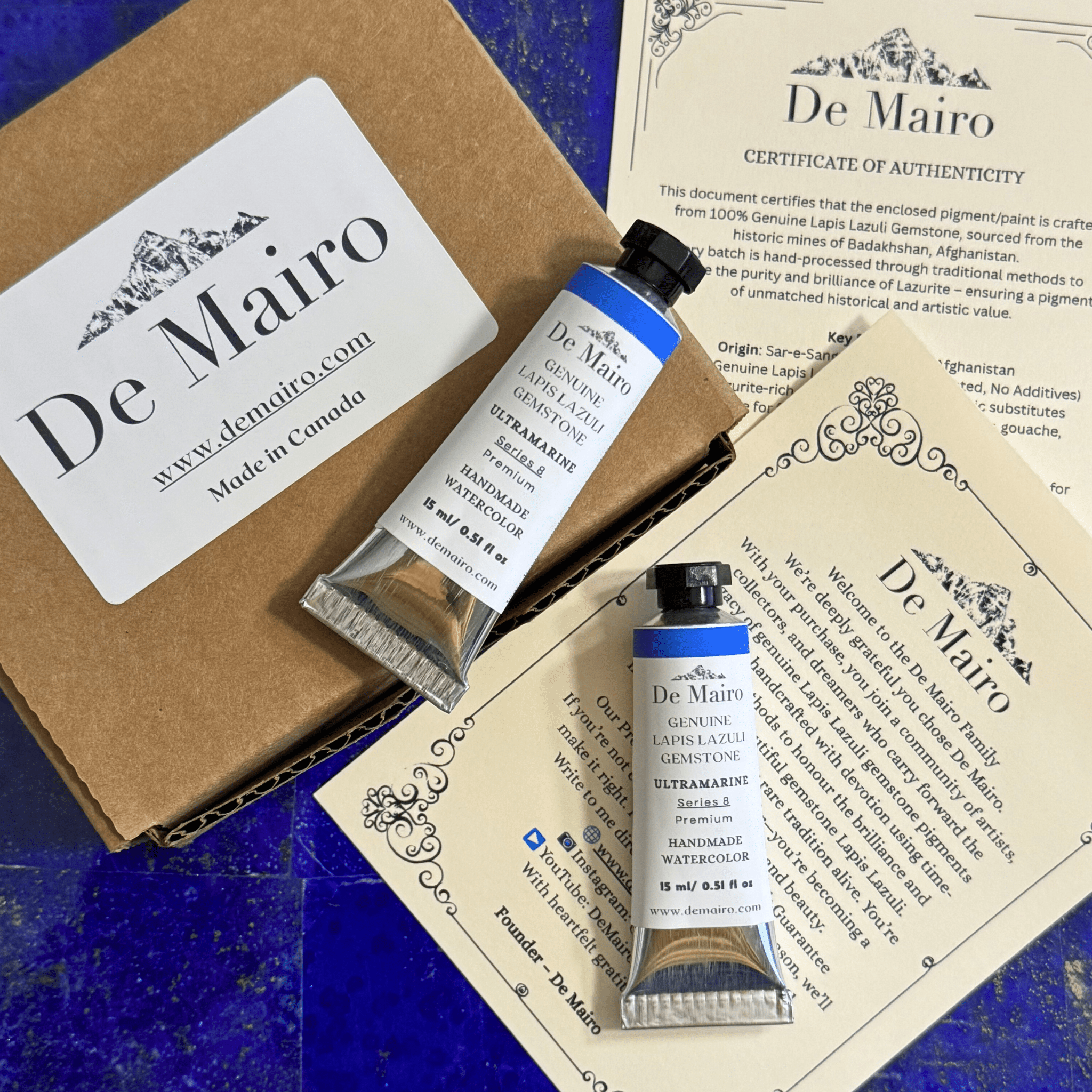 De Mairo watercolor paint tubes with packaging and certificate on a blue surface