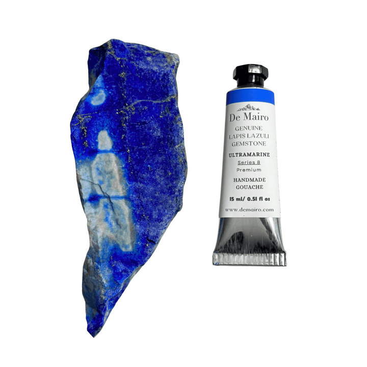 Tube of De Mairo ultramarine paint next to a piece of blue lapis lazuli stone on a white background
