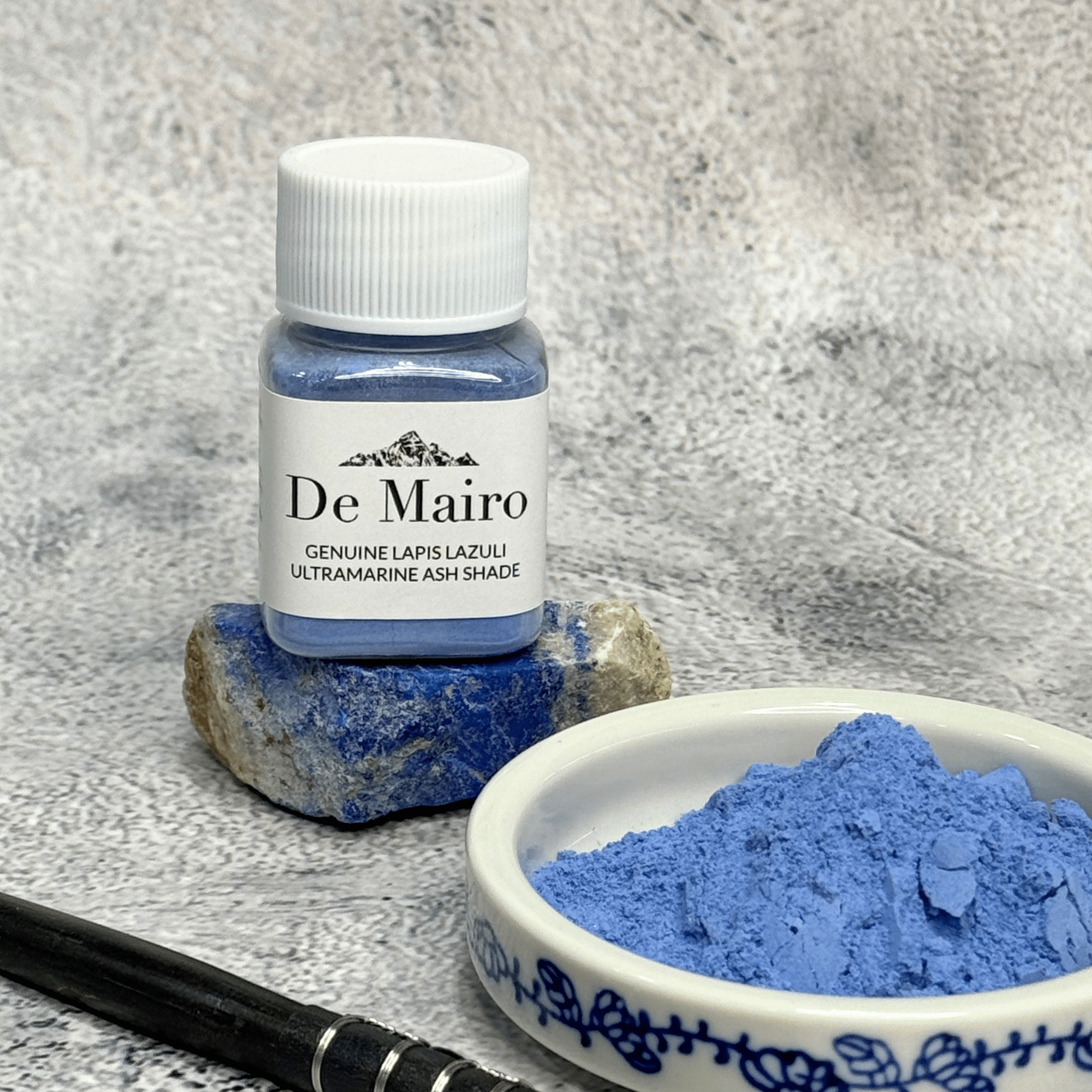 Lapis Lazuli Ultramarine Ash Pigment jar on a lazuli rock near a dish with powder pigment in it