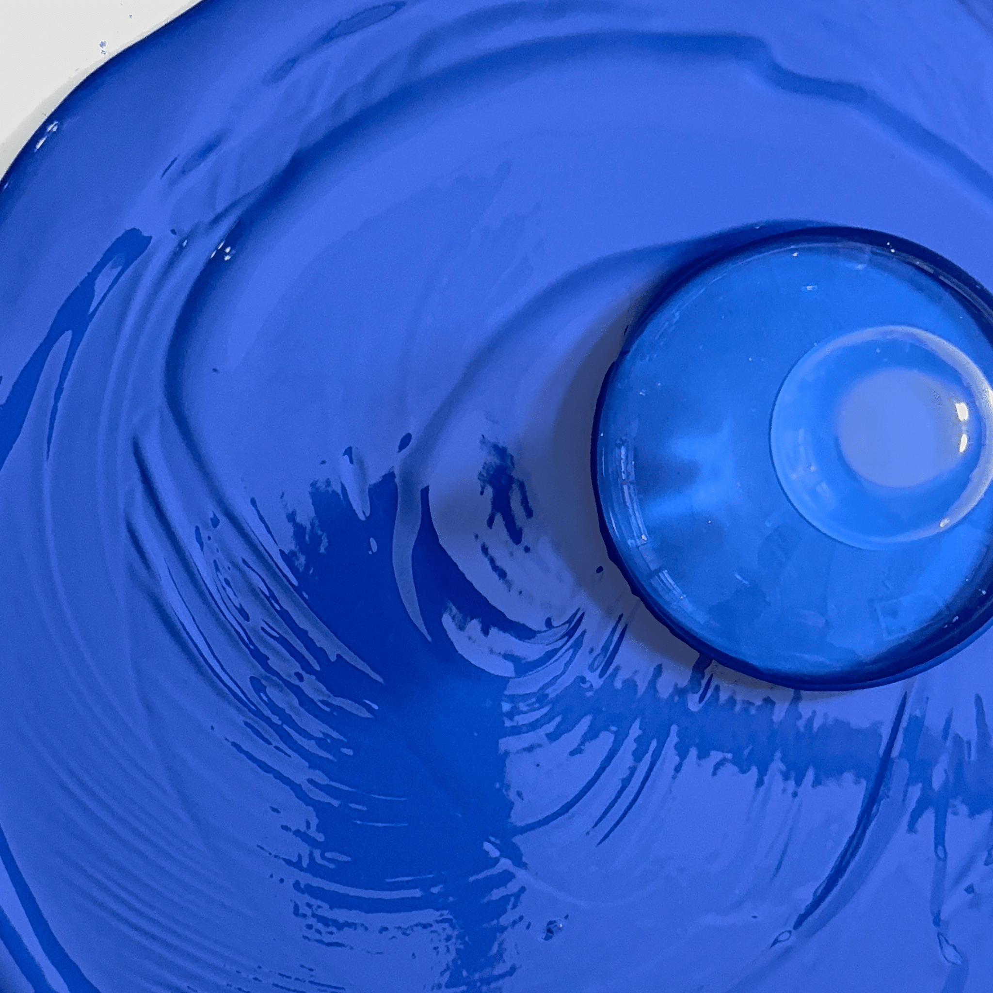 Close-up of an ultramarine gouache paint with paint mixing glass on top.