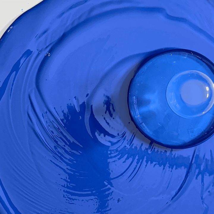 Close-up of an ultramarine gouache paint with paint mixing glass on top.