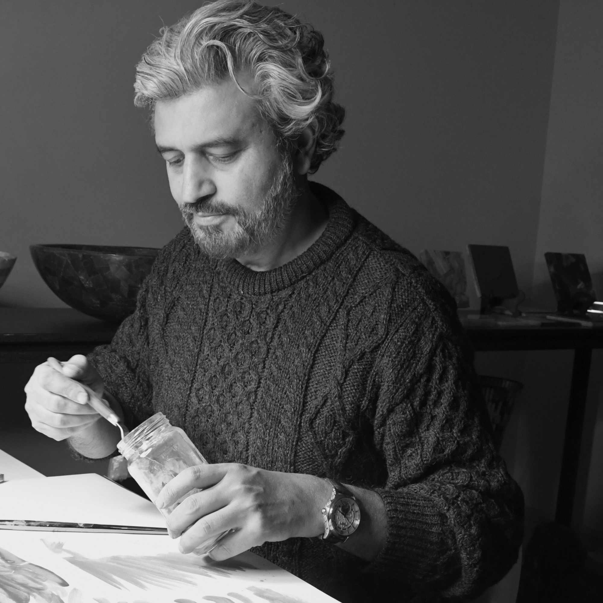 Black and white photograph of Muhammad Irfan extracting lapis lazuli pigment from a jar during the paint-making process