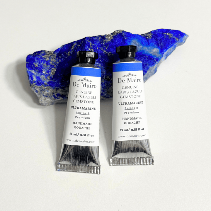 Two tubes of De Mairo ultramarine paint with a lapis lazuli stone on a white background