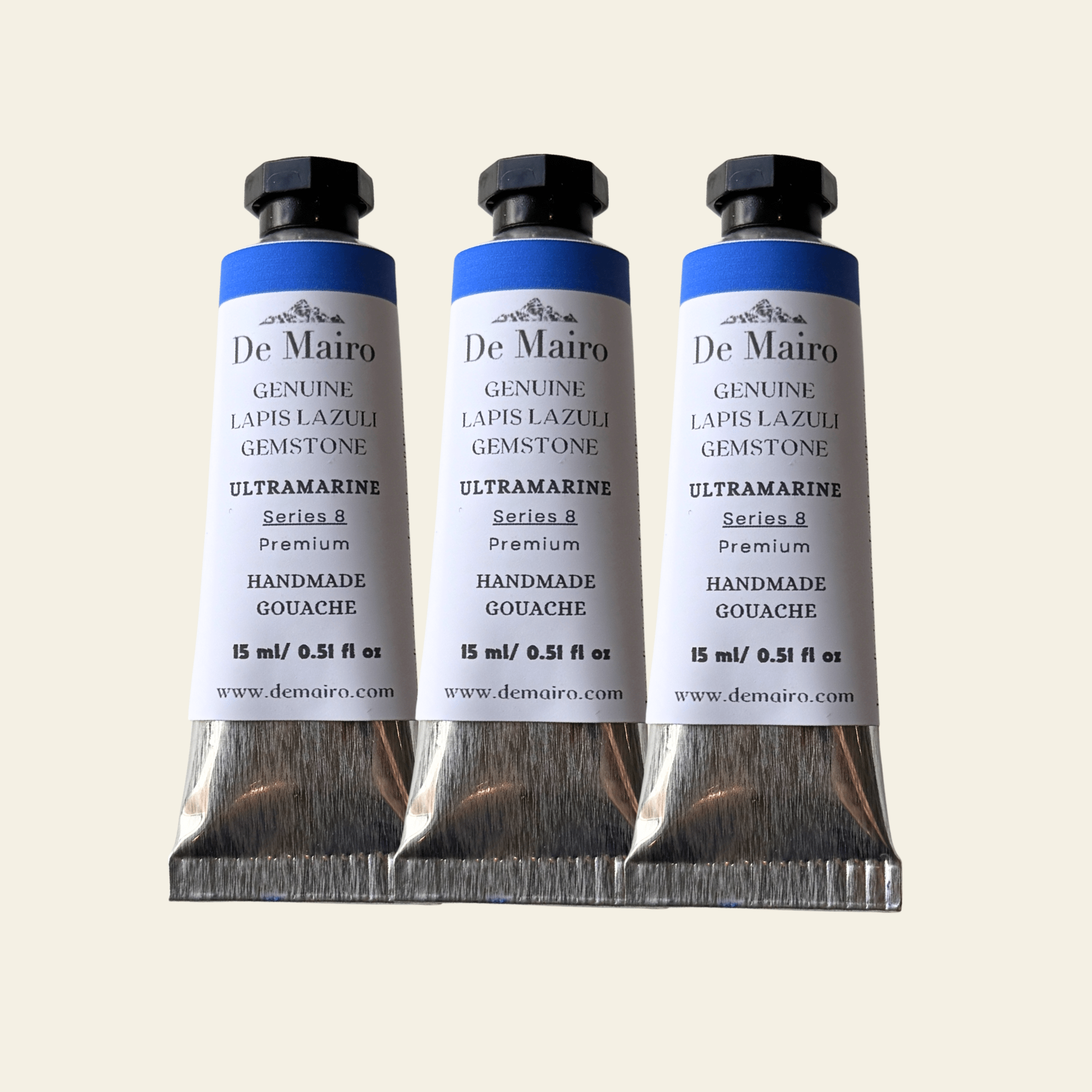 Three De Mairo ultramarine paint tubes on a beige background