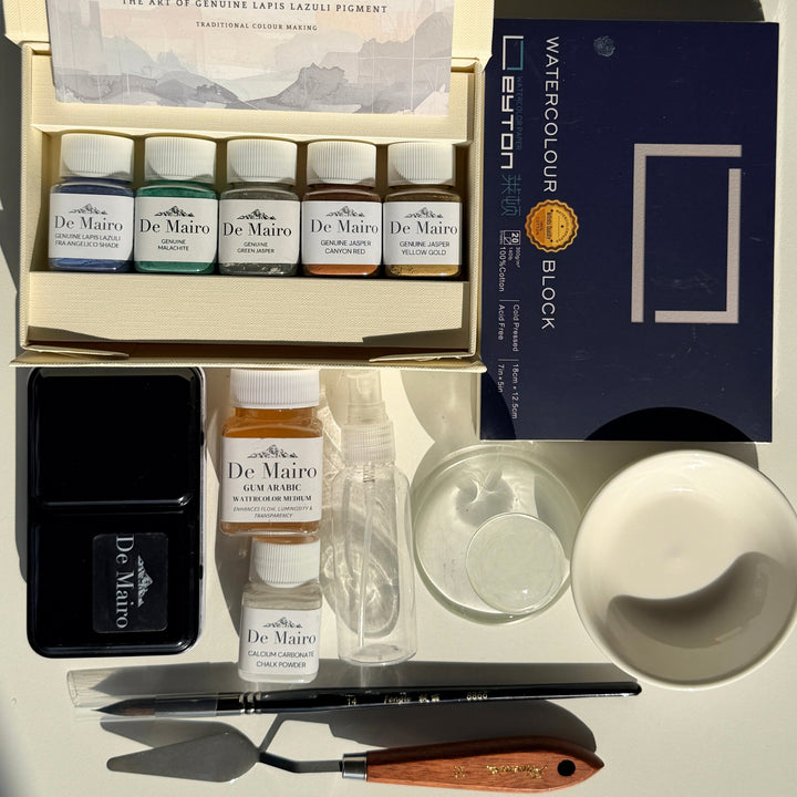 Contents of the De Mairo gemstone paint-making kit: pigments, watercolour tin, glass muller, palette knife and watercolour block