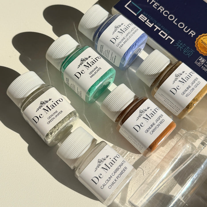 De Mairo genuine gemstone pigment and medium bottles in natural light with watercolour block