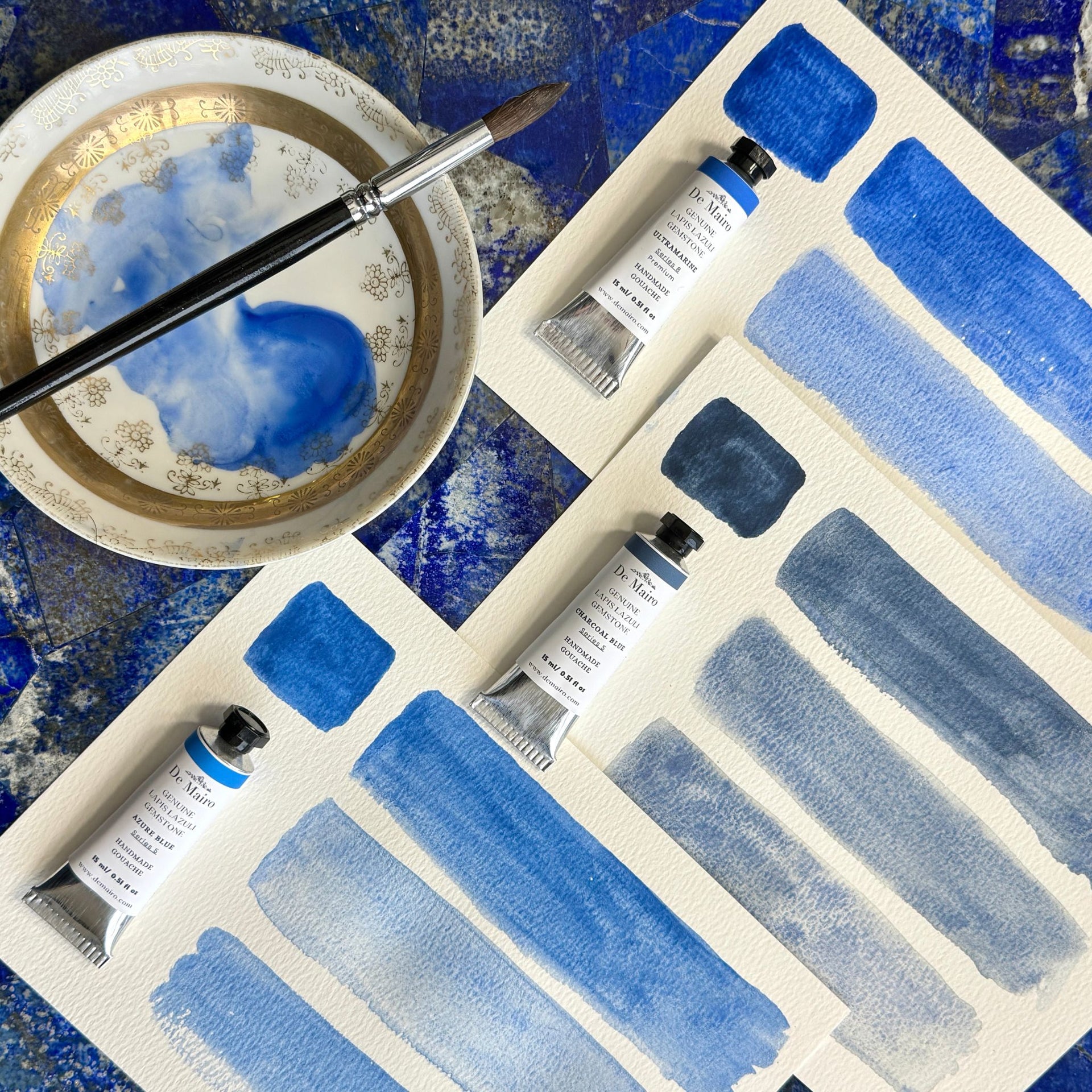 Set of blue gouache tubes with brush strokes on a textured surface